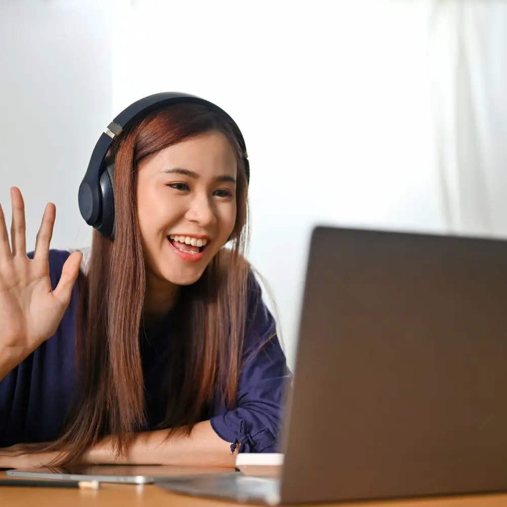 tutor waving to online student on a laptop